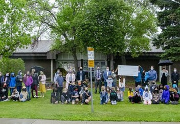 Students in front of the school presenting the cheque